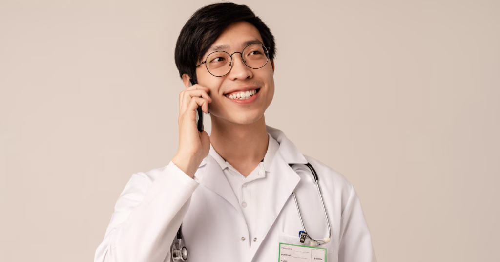 a happy male asian doctor receiving a phone call